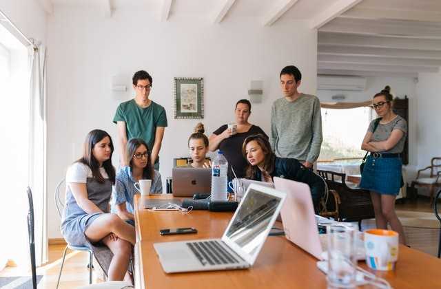 Группа молодых людей смотрят в экран ноутбука и изучают, со скольки лет дают кредит