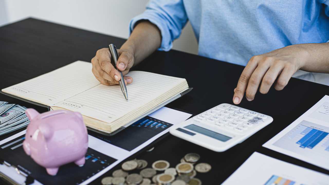 A man sits at a table, counts money and plans his budget based on the statistics of his monthly expenses after the tax refund