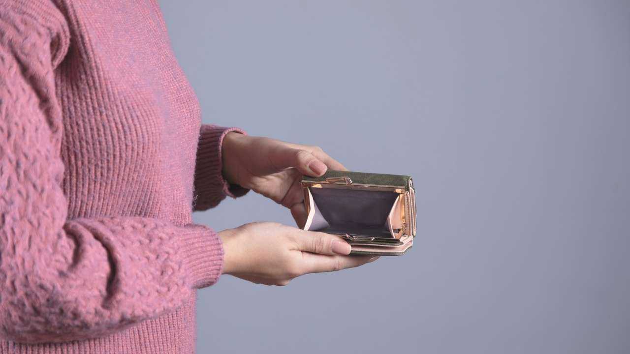 Девушка держит в руках открытый кошелек, в котором нет денег, потому что она не умеет распоряжаться своими финансами