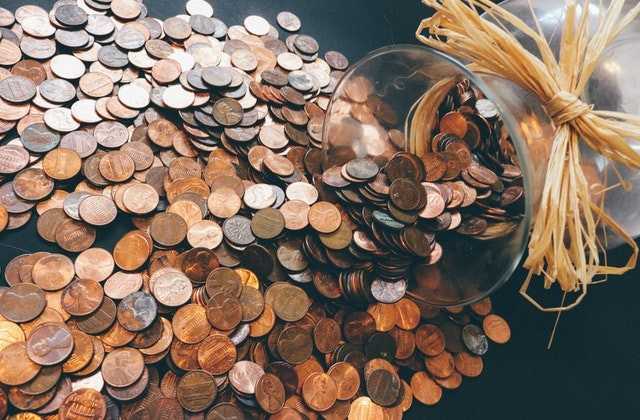 На столе лежит банка, из которой выпало много монет, символизируя богатство, как одно из значений, к чему снятся деньги
