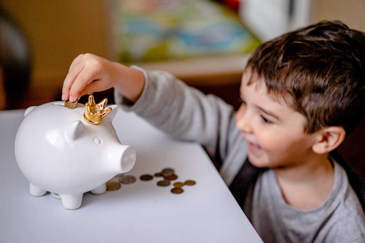 El niño tira dinero a la alcancía.