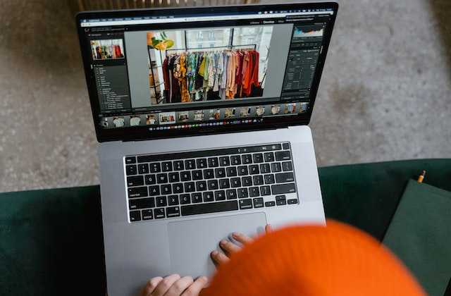 Девушка смотрит на фотографию одежды в ноутбуке, которую она будет продавать в интернете
