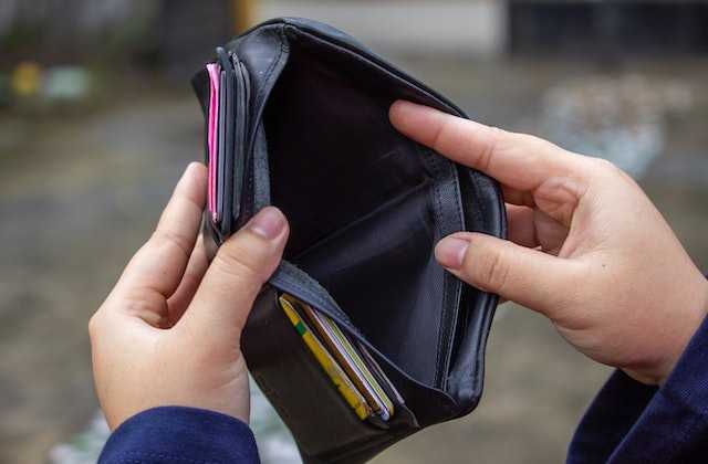 Человек держит в руках пустой черный кошелек и не знает, как погасить кредит если нет денег